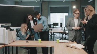 Takım, tartışmalara girerken belgeleri gözden geçirmek için modern ofis alanında işbirliği yapar