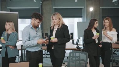 İş adamları modern ofis ortamında bardak tutarken bir tartışmaya giriyorlar.