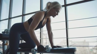 Güneşli bir ortamda modern bir spor salonunda çalışan bir kadının yoğun antrenman seansı.