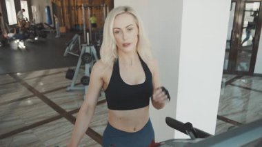 Modern spor salonunda kadın eliptik makine eğitimi alırken fitness hedeflerine ve güç artırımına odaklanıyor