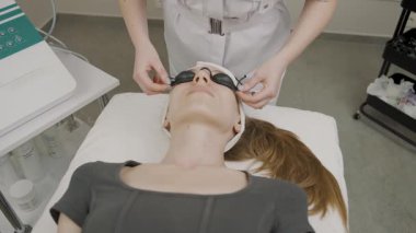 Kız modern bir kozmetoloji stüdyosunda kalıcı makyaj uygulamasına hazırlanıyor.