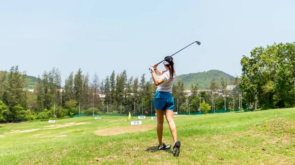 Asian golfer woman swing golf ball practice at golf driving range for relax and healthy care port. Lifestyle and Sport Concept