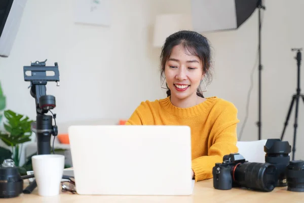 Lifestyle Asia young women photographer and freelance holding a dslr camera in  home office.  Female photographer smiling cheerfully working new project in studio