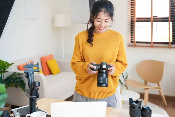 Lifestyle Asia young women photographer and freelance holding a dslr camera in  home office.  Female photographer smiling cheerfully working new project in studio