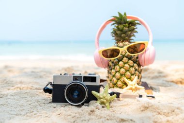Odaklanmayı seç. Partide yaz mevsimi. Güneş gözlüklü hippi Pineapple Fashion ve kumsalda güzel mavi gökyüzü arka planında klasik kamerayla müzik dinlemek. Moda Yaz Tatili Konsepti