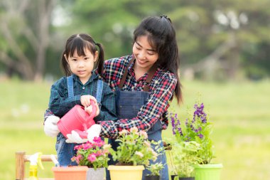 Asyalı kız çocuğu annesine su vermesine ve bitki ağacını filizlendirmesine yardım ediyor küresel ısınma özelliğini azaltmak ve doğa toprağıyla ilgilenmek için. Çevre Kavramı