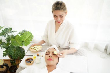 Asya 'lı kadınlar salatalık suratlı kaplıca yapıyorlar. Yüzüne maske takıp spa masajı yapan kızlar. Güzellik masajı sağlıklı sağlık. Spa Thai terapi tedavisi aromaterapi