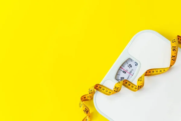 stock image Weight loss control planning.  White scale and measuring tape for body dieting healthy life.  Yellow background. Top view copy space for text