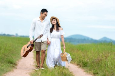 Güneşli bir zamanda mutlu bir balayı geçirin. Asyalı genç çift piknik yapıyor ve tatilde çayırda dinleniyor. Romantik ve aşık. Yaşam tarzı ve Sevgililer Günü konsepti