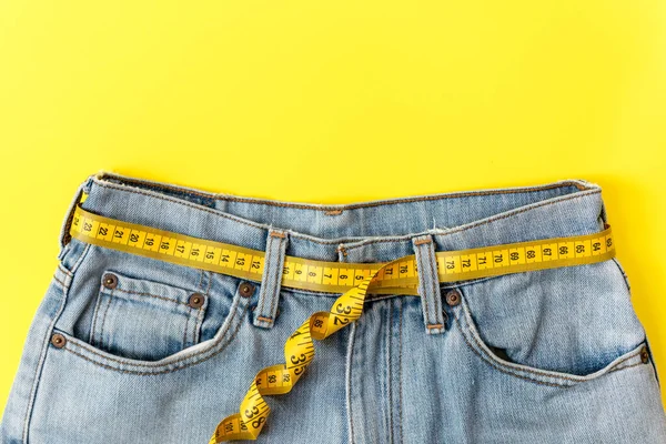 Sağlıklı beslenmeyi planlıyorum. Diyet sağlığı için bel çevresindeki bandı ölçün. Sağlıklı Yaşam Tarzı Konsepti. Sarı renk arkaplanı. Metin için Üst Görünüm ve Kopyalama alanı