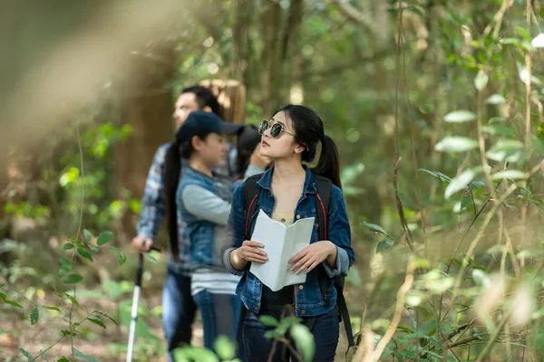 Group asian friends traveler with backpack adventure holding map to find directions and walking relax in the jungle forest outdoor for destination leisure explore education nature on vacation. Travel and Lifestyle Concept