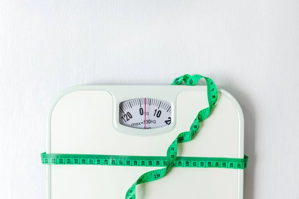 Weight loss control planning.  White scale and measuring tape for body dieting healthy life.  White background. Top view copy space for banner
