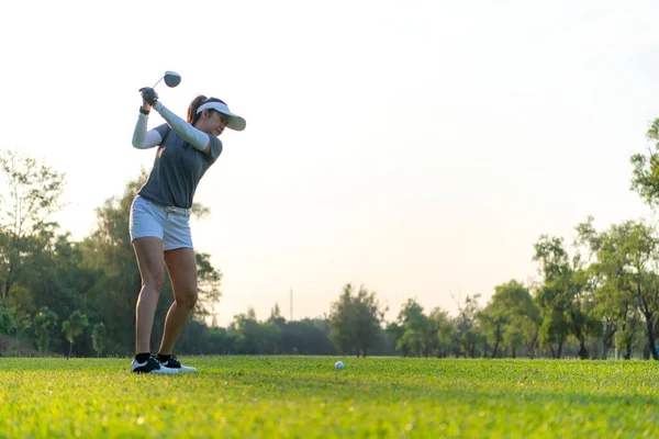 Golfer women sport course golf ball fairway. People lifestyle woman playing game golf approach tee of on the green grass sunset background. Asian female player game shot in summer. copy space for tex