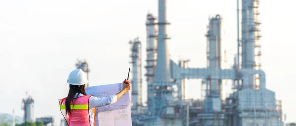 Engineers woman holding blueprint and report schedule for workers security control at power plant energy industry. Engineer and industry Concept, copy space for banner