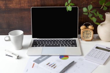 Bilgisayarı ve grafikleri olan iş yeri şemaları ve beyaz fincan kahve içeceğini finanse ediyor. Eski ahşap arka plan. İş Nesnesi Konsepti