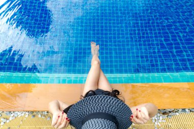 Yaz zamanı ve tatiller. Moda tarzı olan, büyük şapkalı, rahat ve lüks yüzme havuzunda mutlu bir kadın hayatı. Yazın oteldeki sahil evinde. Yaz Konsepti, üst görünüm