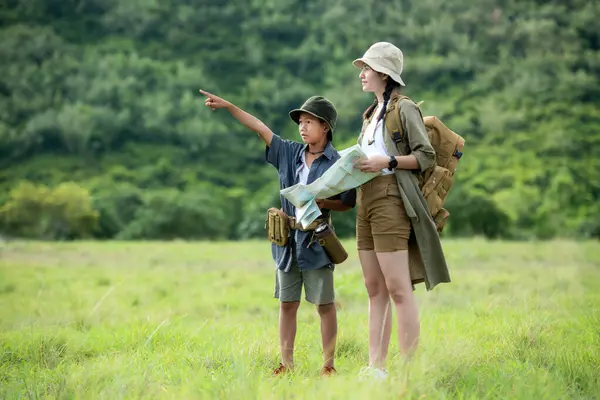 Group family children checking map and pointing in the jungle adventure.   Asia people tourism for destination leisure trips for education and relax in nature park.  Travel vacations and Life Concept