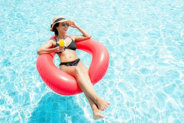 Yaz zamanı ve tatiller. Portakal suyu içen, lüks yüzme havuzunda rahatlayan, oteldeki tatil köyünde mutlu bir kadın yaşam tarzı. Yaz Konsepti