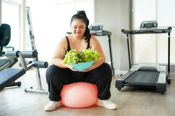 Asian woman eating healthy food salad before fitness exercise for lose weight.  People overweight training and exercising in gym for body healthy