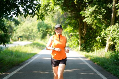 Sağlıklı bir kadın dışarıda koşuyor ve antrenman yapıyor. Asyalı koşucular spor salonu, spor salonu, doğa parkı geçmişi. Sağlık ve Yaşam Tarzı Konsepti