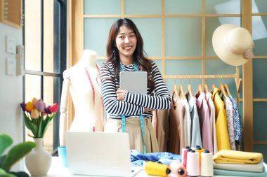 Owner business asian young women fashion designer working on her designer in the showroom,  Lifestyle Stylish tailor taking measurements on mannequin for cutting cloths in studio