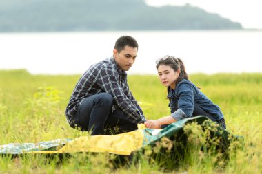 Nehir ve çayırın yakınına kamp kurmaya yardım eden bir arkadaş. Gençleri bir araya toplayın. Aile seyahatleri, macera gezileri, tatiller, tatil merkezleri.