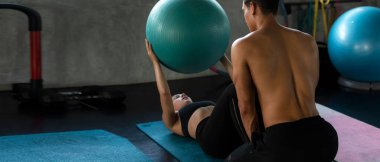 Yoga topunu eğiten antrenör, spor salonunda bir kadınla vücut zayıflığı ve sağlıklı bakımı için egzersiz yapıyor. Beden eğitimi eğitmeni müşterileriyle spor yapıyor. Sağlıklı Spor Konsepti