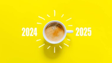 Mutlu yıllar ve Mutlu Noeller 2025. Bir fincan kahve değiştirip 2024 'ten 2025' e kadar sarı arkaplandan yükleyin. Başlangıç ve Yeni Yıl Konsepti. Boşluğu kopyala 