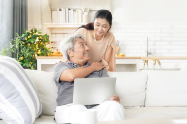 Asya 'nın mutlu yaşlı çifti oturma odasında sarılıp kucaklaşıyor. Emekli olduktan sonra evde dizüstü bilgisayarla çalışan kıdemli bir adam.