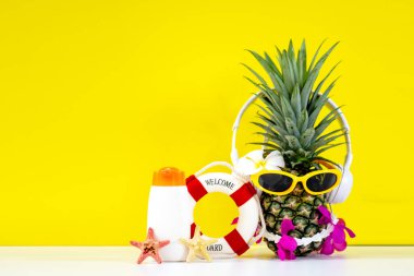Yaz partisi hipster ananas modası güneş gözlüğü ve müzik dinlemek ve koruyucu güneş kremi ya da sağlıklı bakım için güneş kremi ve güneş kremi sarı arka planda beyaz plastik şişeler, tatilde yaz aksesuarları. Yaz Konsepti