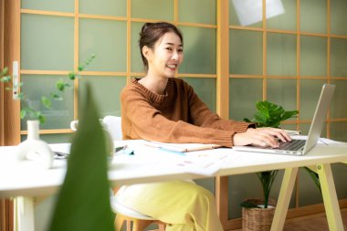 Young people work from home checking report for presentation with laptop morning relax at home. Asia woman meeting conference connect online with office.  Business and Technology Concept
