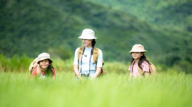 Grup çocukları orman macerasında haritayı kontrol ediyor. Asyalılar eğitim için tatil gezileri için turizm yapıyor ve doğa parkında dinleniyor. Dağ arka planı