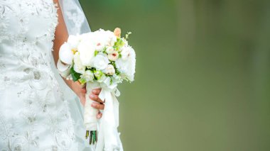 Gelin edding buketini tutuyor. Gelinin gelinliği bahçede. Doğa yeşili Arkaplan