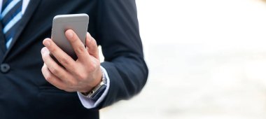 Şehirdeki finansal verilerle çalışmak için akıllı telefon kullanan iş adamını kapatın. İş Konsepti