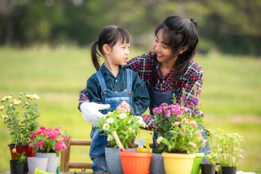 Asyalı kız çocuğu annesine su vermesine ve bitki ağacını filizlendirmesine yardım ediyor küresel ısınma özelliğini azaltmak ve doğa toprağıyla ilgilenmek için. Çevre Kavramı