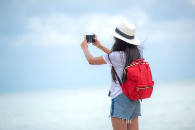 Happy traveler and tourism young women travel summer on the beach. Asian smiling people holding smartphone take photo  for relax outdoor destination leisure trip travel in holiday
