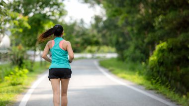 Sağlıklı bir kadın dışarıda koşuyor ve antrenman yapıyor. Asyalı koşucular spor salonu, spor salonu, doğa parkı geçmişi. Sağlık ve Yaşam Tarzı Konsepti