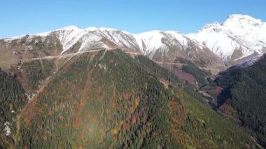 Karla kaplı dağların, ormanların ve sonbahar renklerinin görüntüleri.