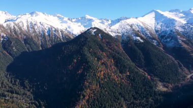 Karla kaplı dağların, ormanların ve sonbahar renklerinin görüntüleri.