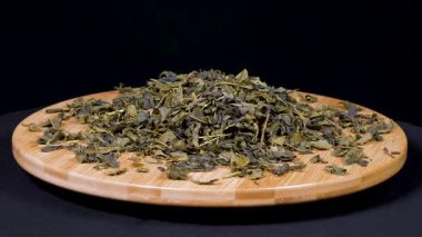 Siyah arkaplanda kurumuş yeşil çay yapraklarının yakın çekim görüntüleri..