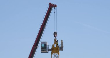 Kule vinçlerini toplayan ve güvenlik önlemleri almadan tehlikeli yükseklikte çalışan işçilerin görüntüleri..