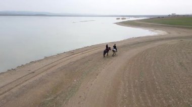 Göl kıyısında ata binen insanların görüntüleri..