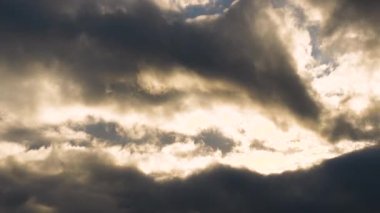 Yağmur ve fırtına bulutlarıyla kaplı kasvetli bir gökyüzünde, bulutların arasındaki ışık demetlerinin zamanlanmış görüntüleri..