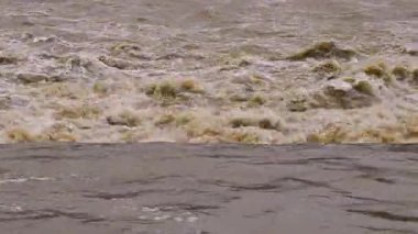 Yağmur ve fırtınadan sonra akan çamurlu ve bulanık dere görüntüsü.