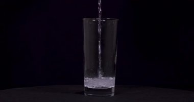 Siyah arka planda soda ve limonların cama döküldüğü yakın çekim görüntüleri.