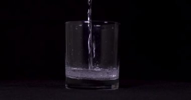 Suyun siyah arkaplanda cama aktığını gösteren yavaş çekim görüntüleri..