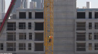 Kule vinçlerini toplayan ve güvenlik önlemleri almadan tehlikeli yükseklikte çalışan işçilerin görüntüleri..