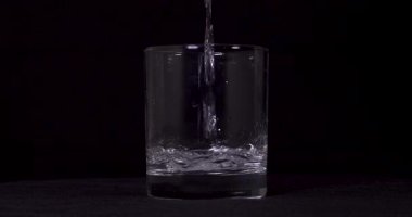 Suyun siyah arkaplanda cama aktığını gösteren yavaş çekim görüntüleri..