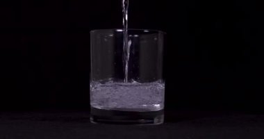 Siyah arka planda soda ve limonların cama döküldüğü yakın çekim görüntüleri.