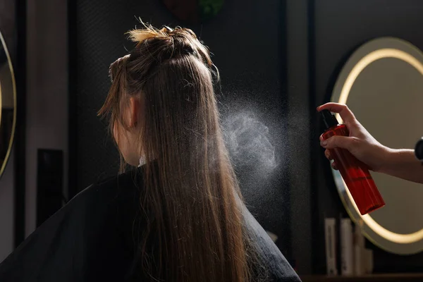 hairdresser applies hair care product with spray, hair styling close-up